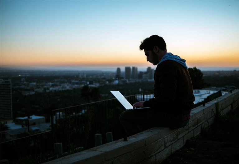 Human being sitting with laptop in city viewpoint
